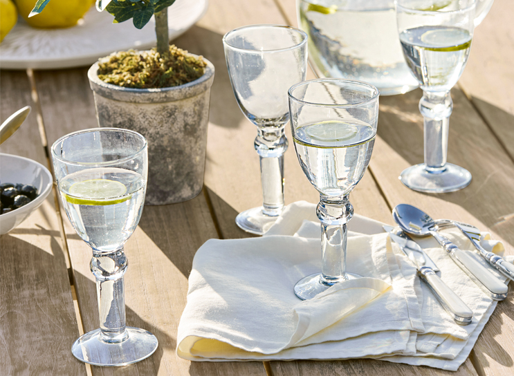 Waterglazen met citroen op houten tafel met wit servet en bestek, mediterrane stijl