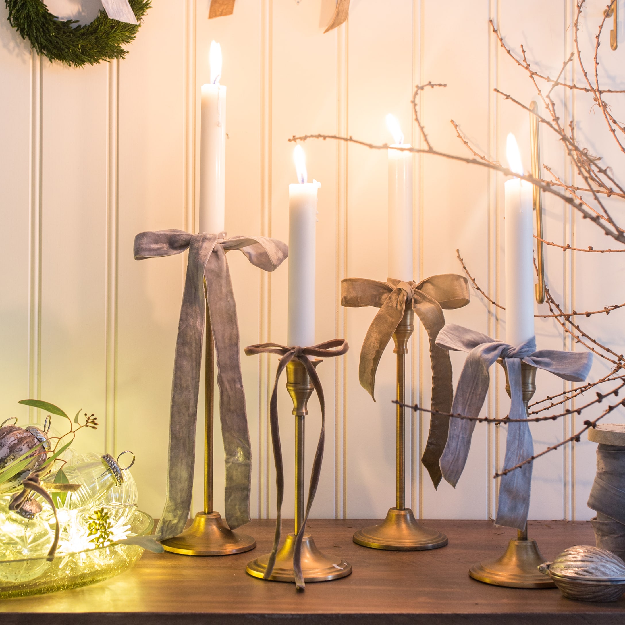 Set messing kandelaars met witte kaarsen en fluwelen linten op houten tafel