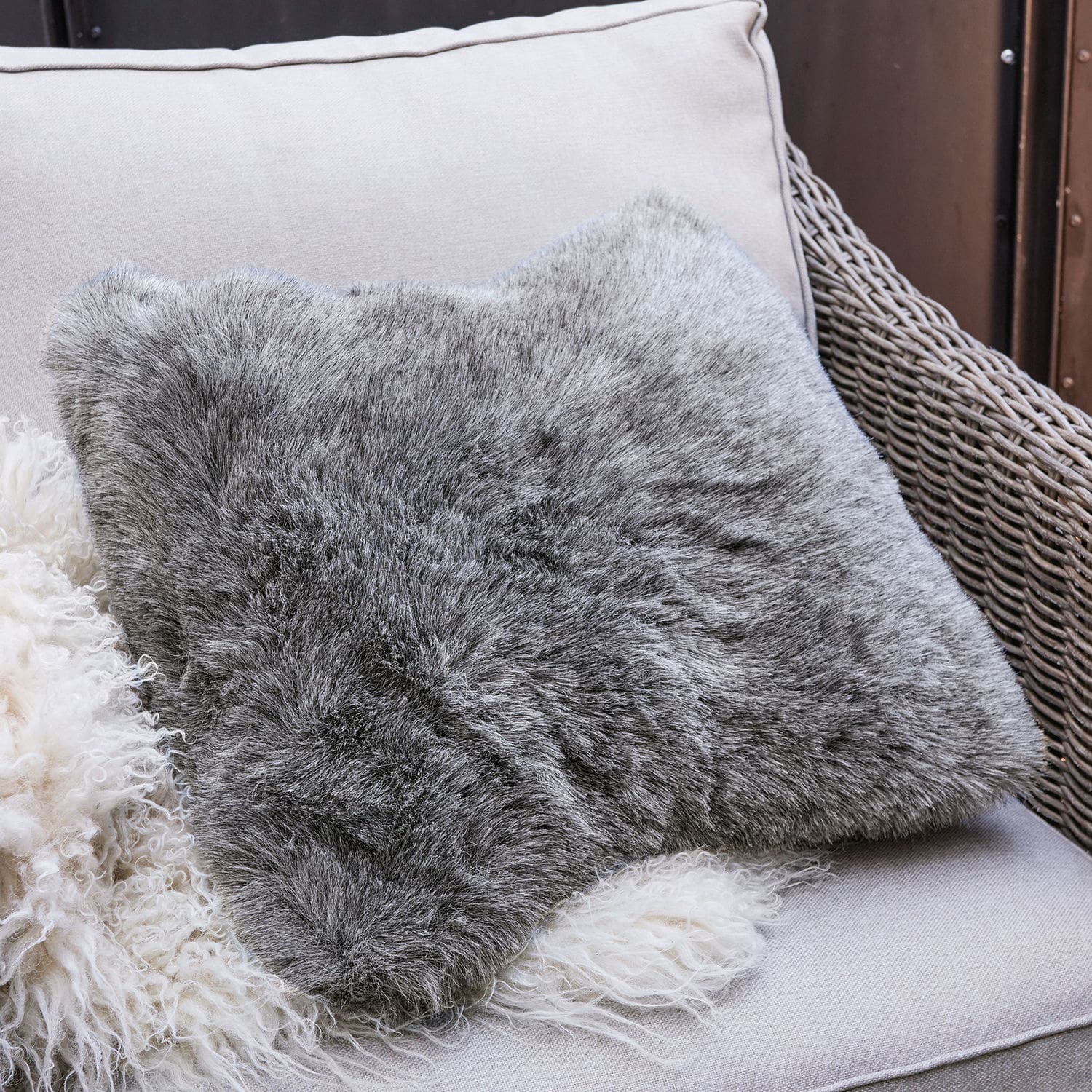 Grijs kussen van zacht bont op lichte bank, comfortabele woondecoratie