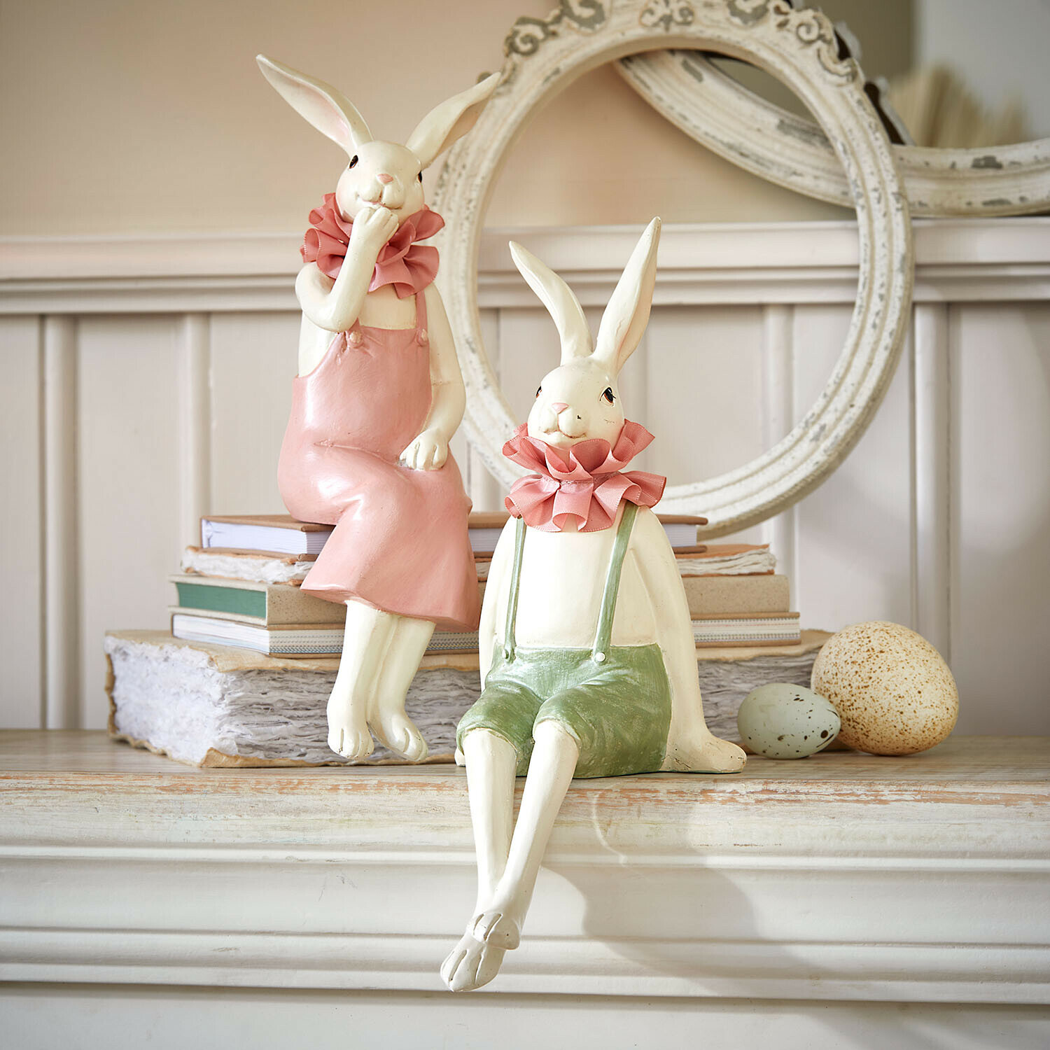 Decoratieve keramische konijnenfiguren in pastelkleuren op schoorsteenmantel met boeken en eieren