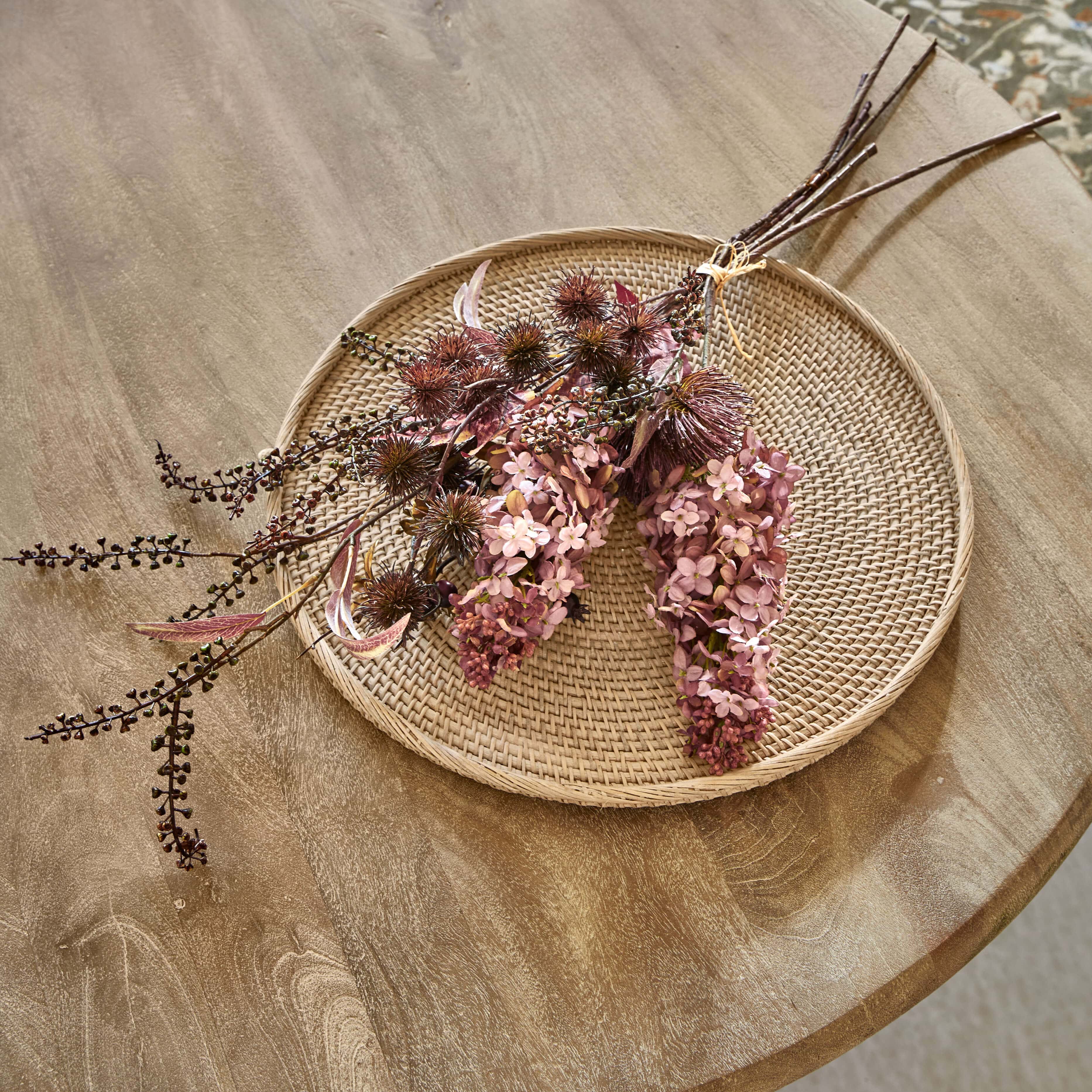 Decoratief boeket gedroogde bloemen in roze en bruine tinten op een gevlochten rotan schaal voor interieur