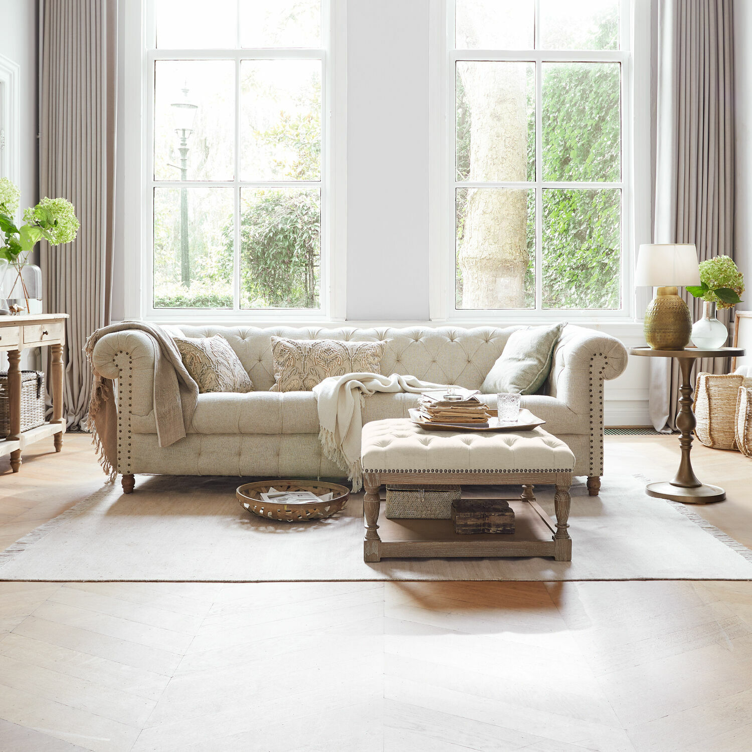 Bank Parpeville Beige gestoffeerde stoffen bank met geborduurde kussens en houten salontafel in lichte woonkamer
