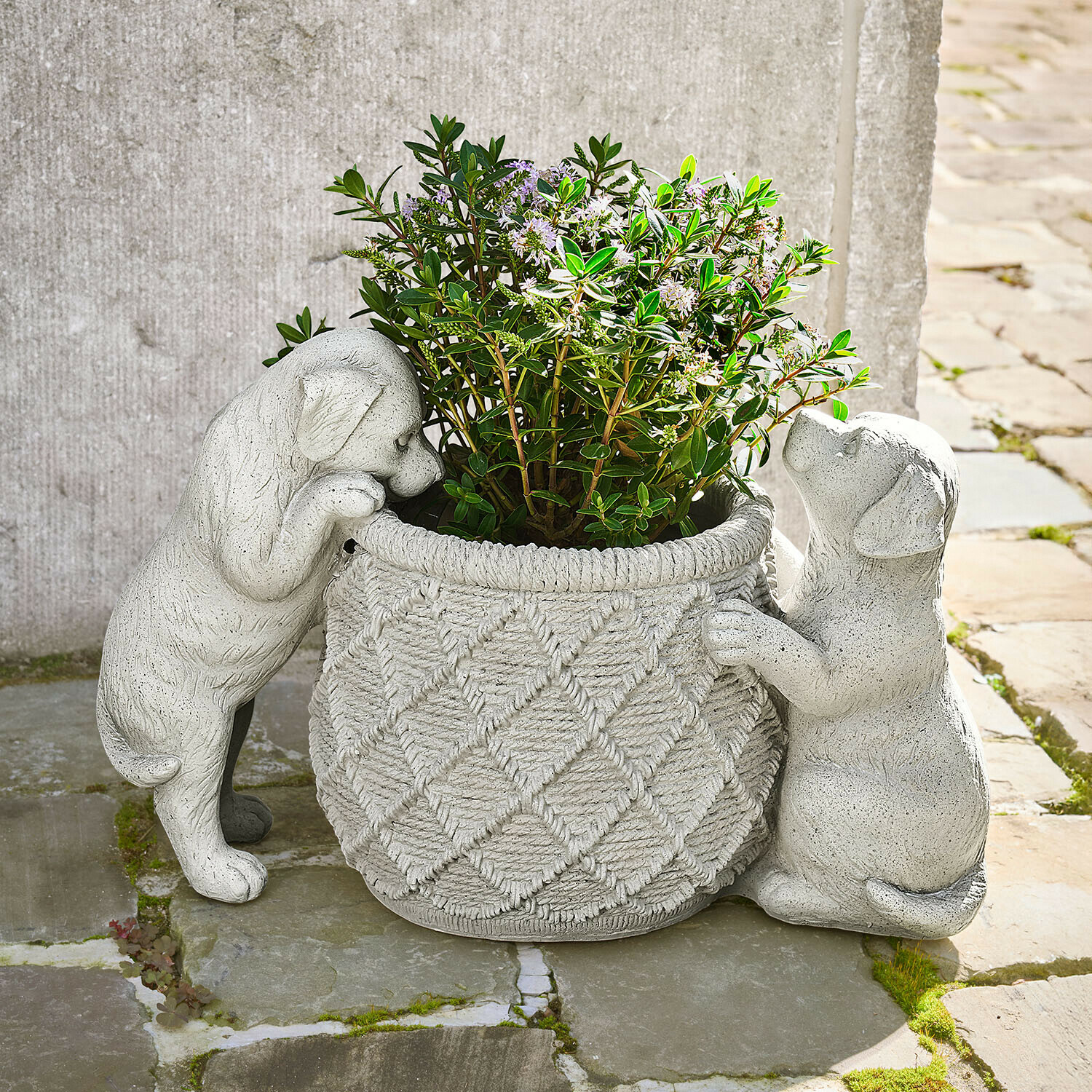 Sierpot Marnja Grijze stenen bloempot met twee puppyfiguren die een plant met groene bladeren vasthouden