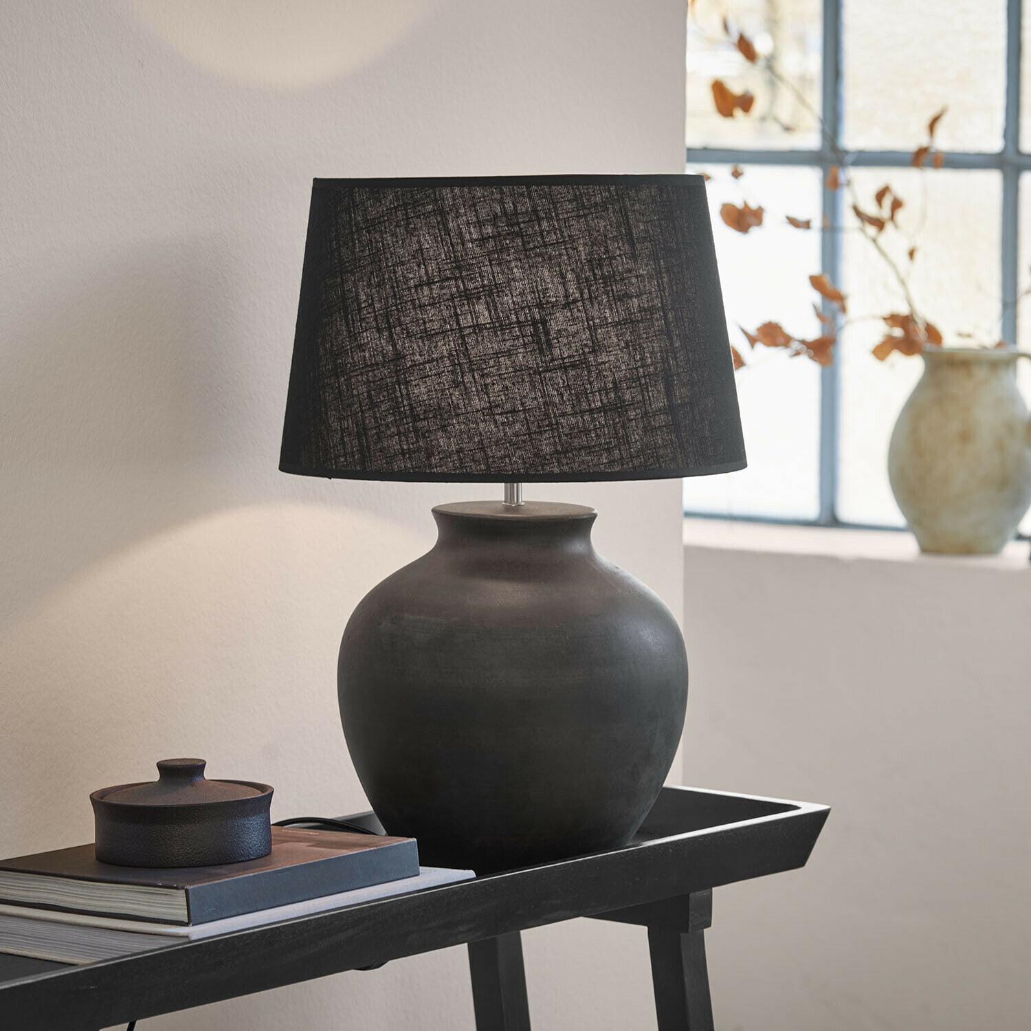 Tafellamp Branver Zwarte keramische tafellamp met stoffen kap op tafel met boeken en decoratie