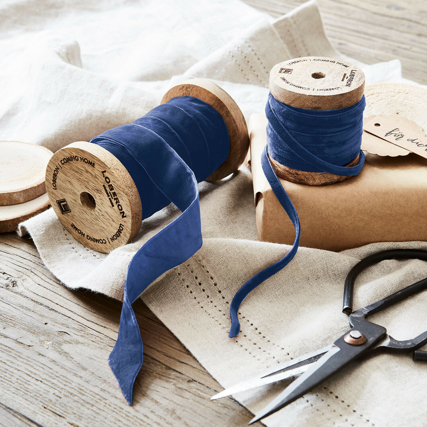 Fluwelen lint set van 2 Liandis Blauwe fluwelen lint op houten spoelen met schaar op linnen doek, decoratie en knutselmateriaal