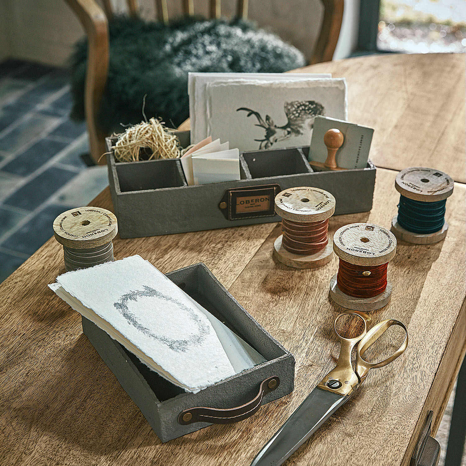 Fluwelen lint set van 4 Hilary Grijze vilten dozen met handvatten en houten spoelen met gekleurde koorden op houten tafel