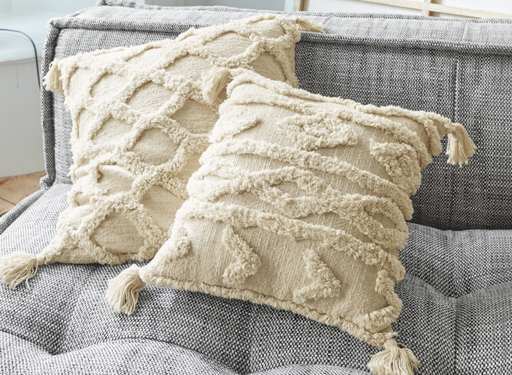 Beige decoratieve kussens met franjes en geometrisch patroon op grijze stoffen bank
