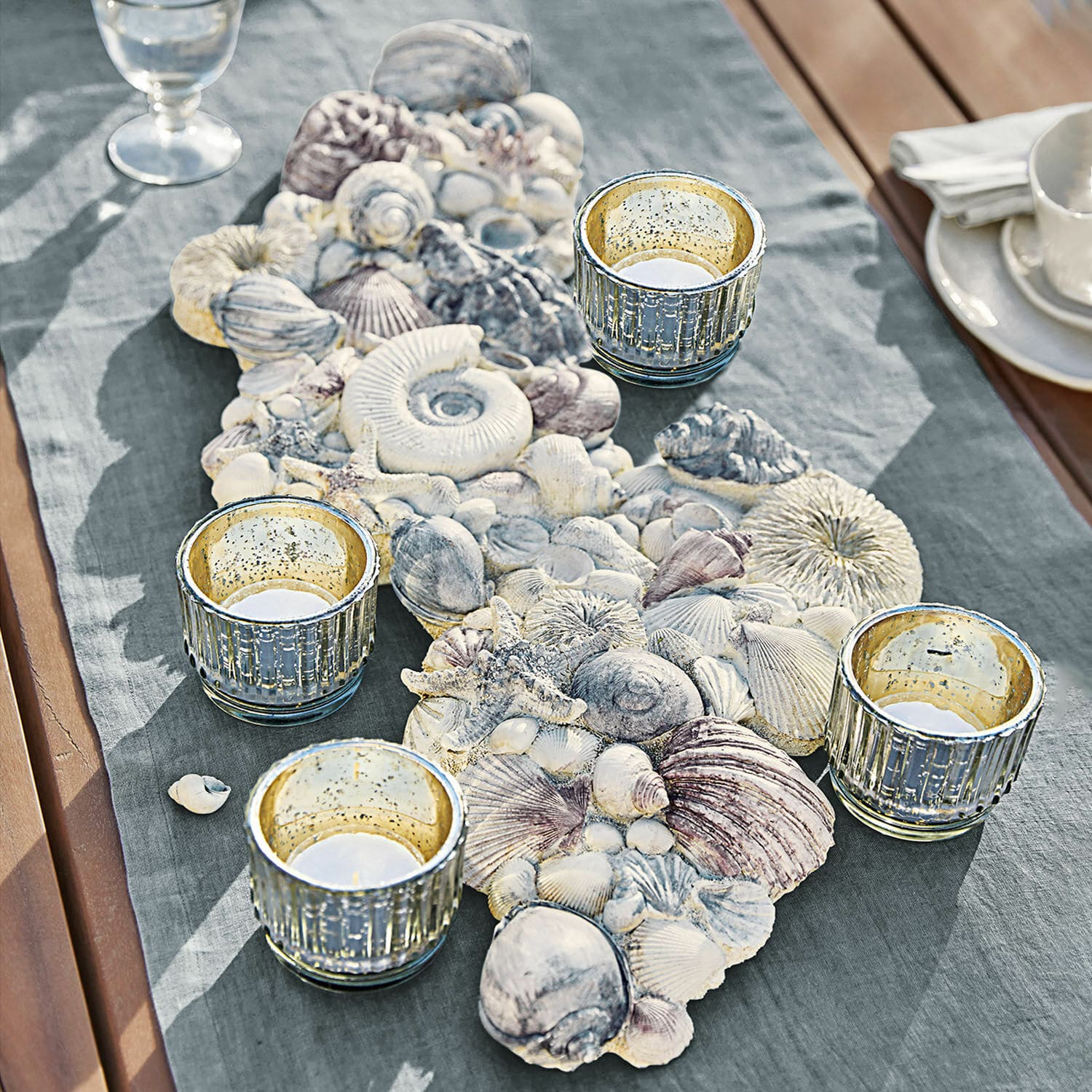 Sierobject van schelpen Potnarvin Decoratieve tafelloper met schelpen en vier glazen theelichthouders op houten tafel met stof