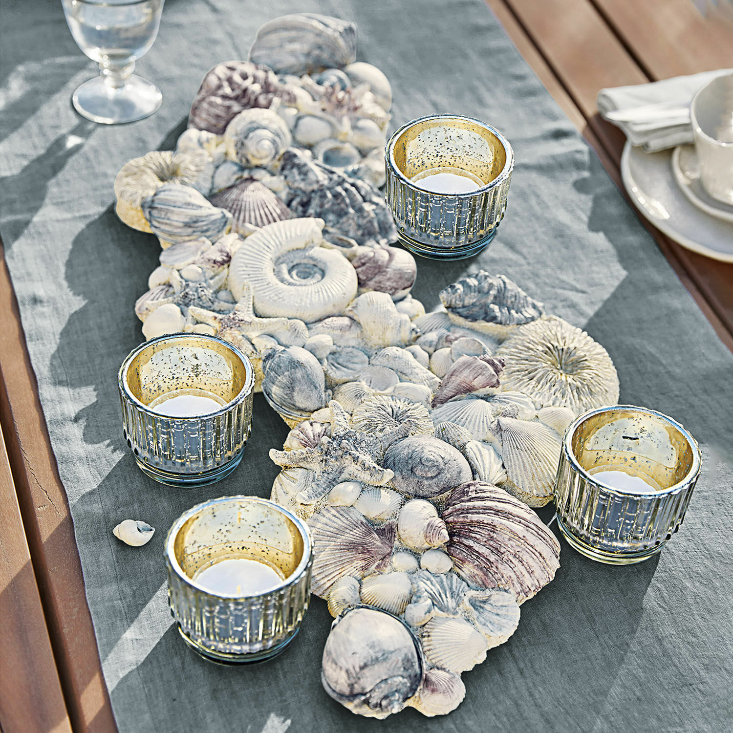 Sierobject van schelpen Potnarvin Decoratieve tafelloper met schelpen en vier glazen theelichthouders op houten tafel met stof