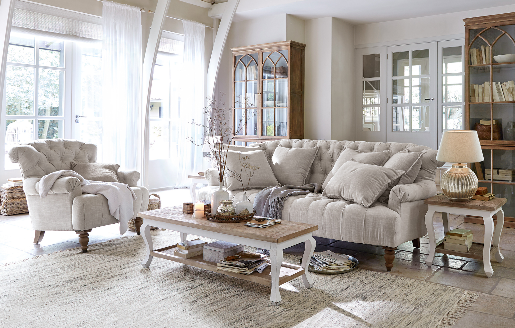 Gezellige landelijke woonkamer met beige stoffen bank en stoel en lichte houten meubels