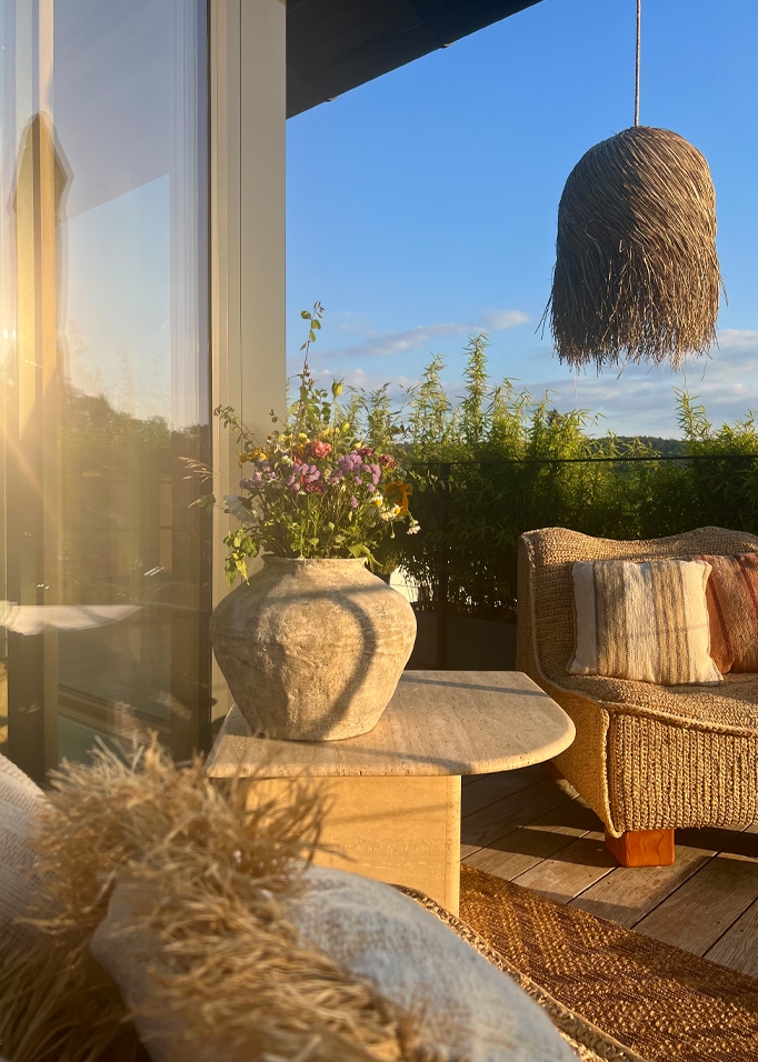 Gezellig balkon met rotan stoel, stenen tafel en vaas met bloemen in natuurlijke kleuren