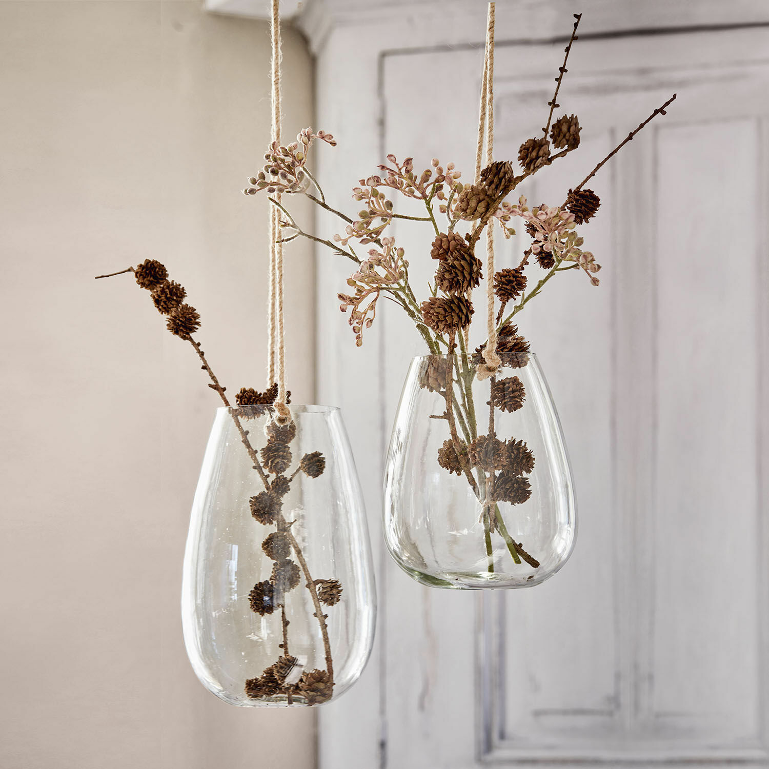 Hangende glazen vazen met natuurlijke takken en dennenappels voor interieurdecoratie