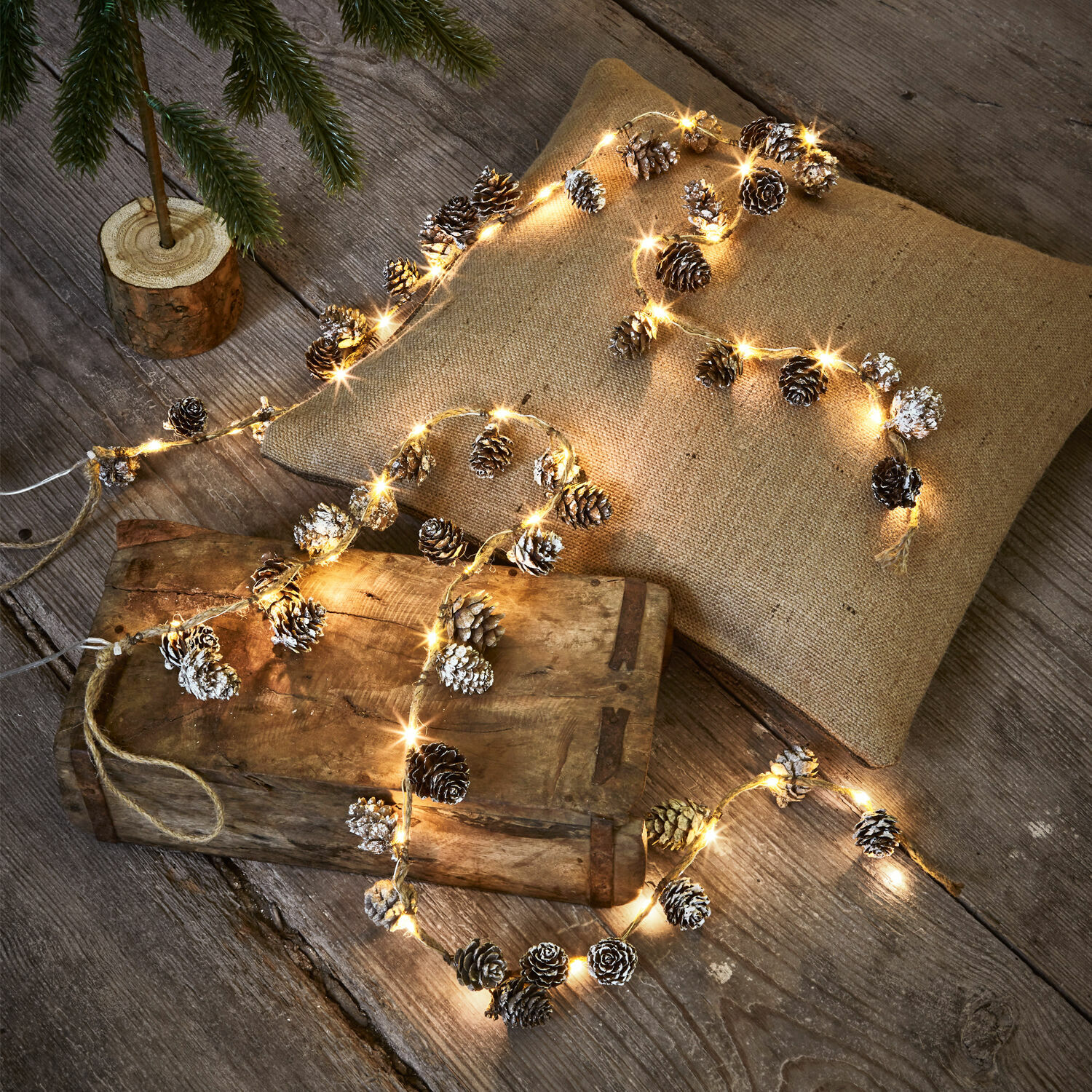 Ledlichtsnoer set van 2 Crane Lichtsnoer met dennenappels en warm licht op houten tafel en linnen kussen sfeervol gelegd