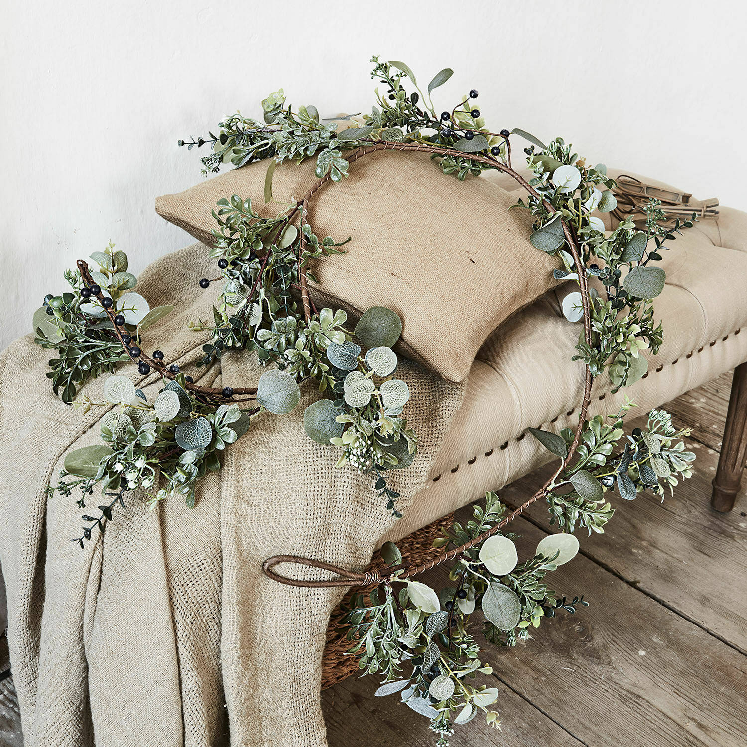 Guirlande Grand Decoratieve krans met groene bladeren en zwarte bessen op beige stof en houten bank