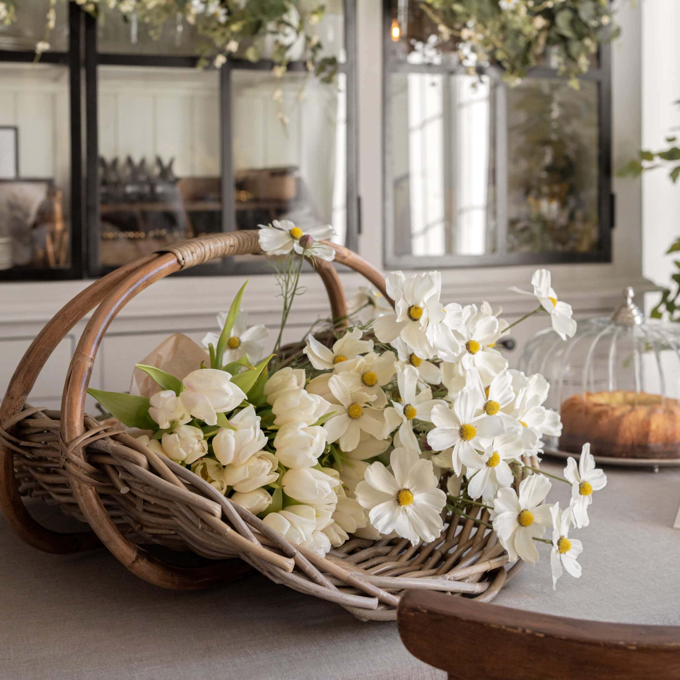Rieten mand met witte tulpen en decoratieve bloemen op tafel in lichte kamer