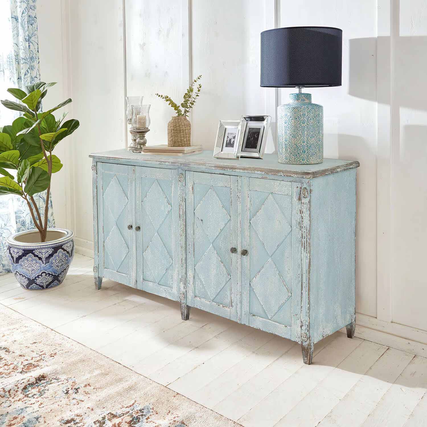 Blauwe houten dressoir met vintage verweerde look in lichte kamer met lamp en plant