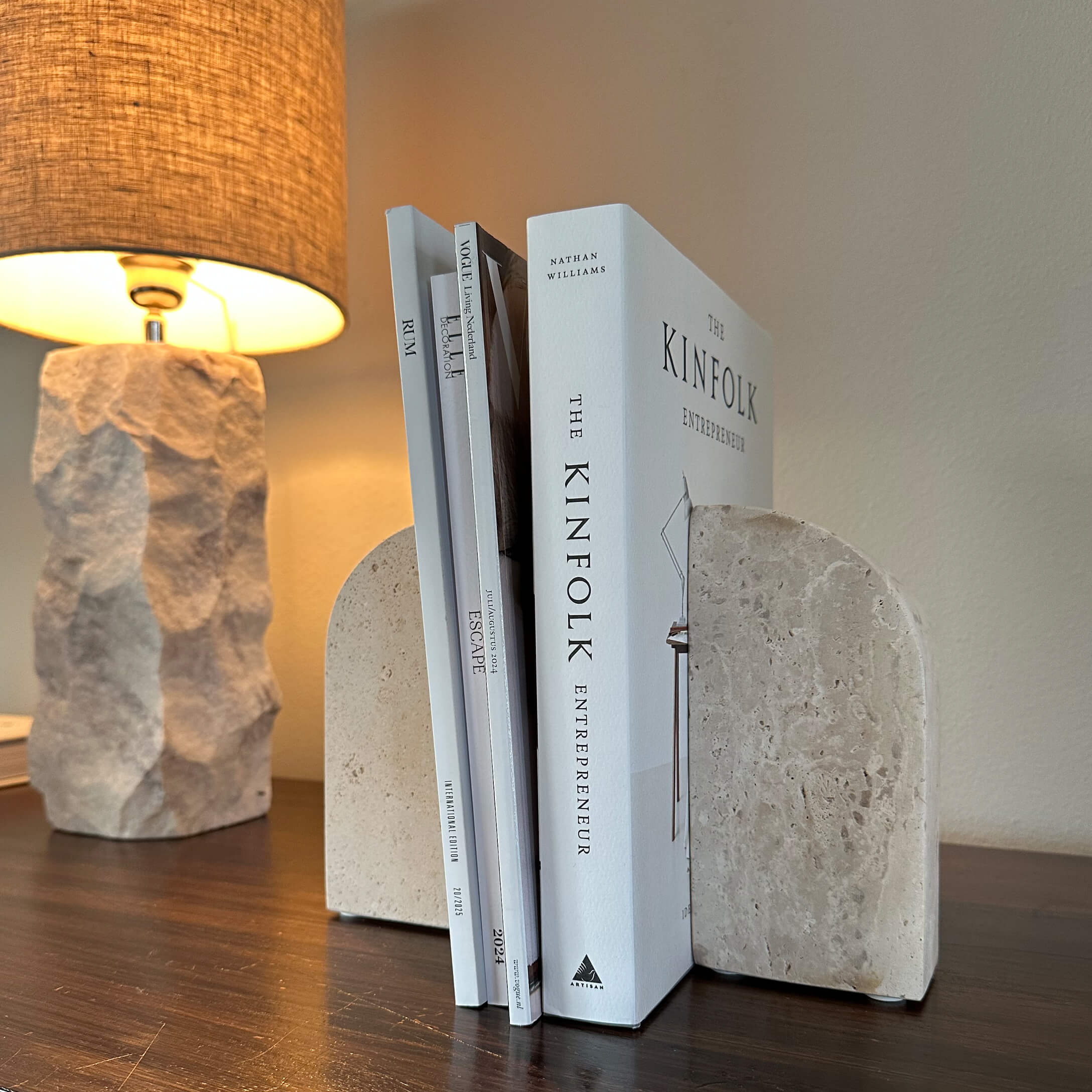Beige stenen boekensteunen op houten tafel met lamp op de achtergrond
