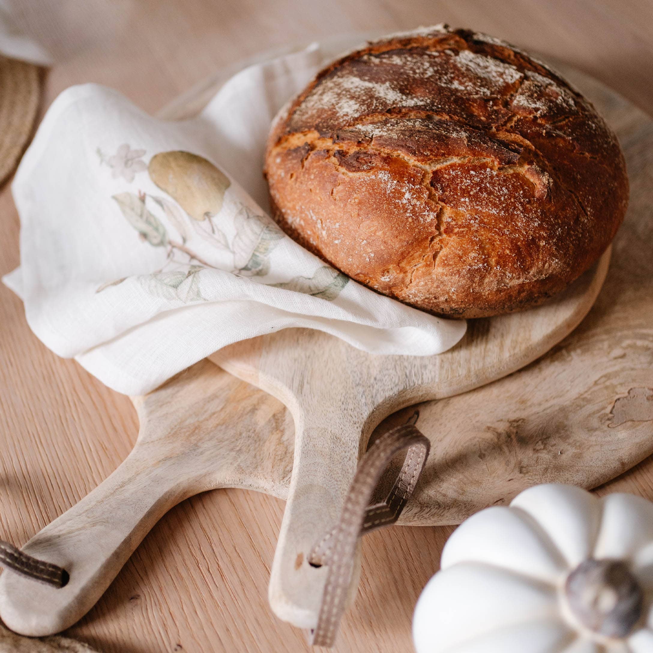 Brood op houten snijplank met linnen doek en witte decoratieve pompoen op tafel