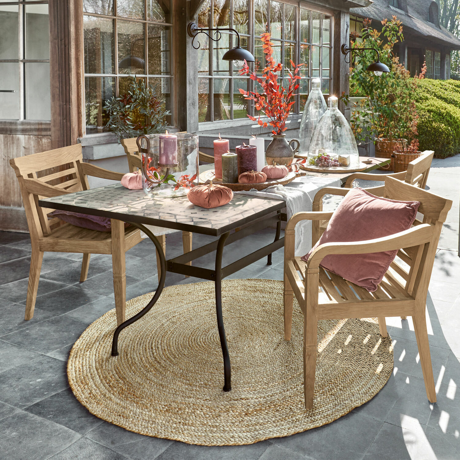 Tafel Labaroche Tafel met metalen poten en mozaïekblad, gedecoreerd met kaarsen en roze kussens op houten stoelen