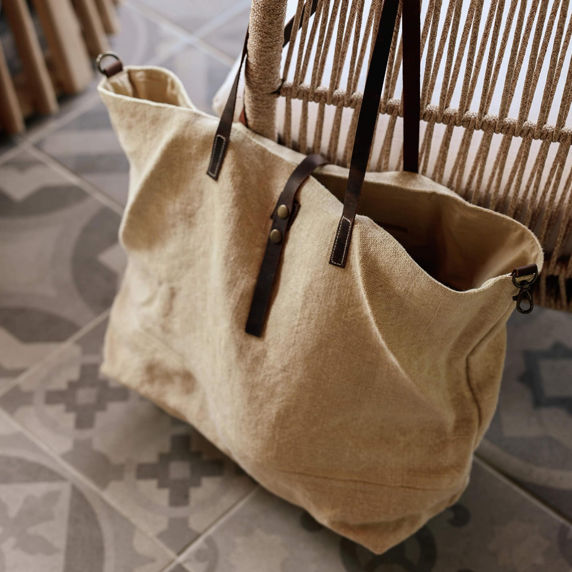 Beige stoffen tas met donkerbruine leren handvatten op patroon tegelvloer