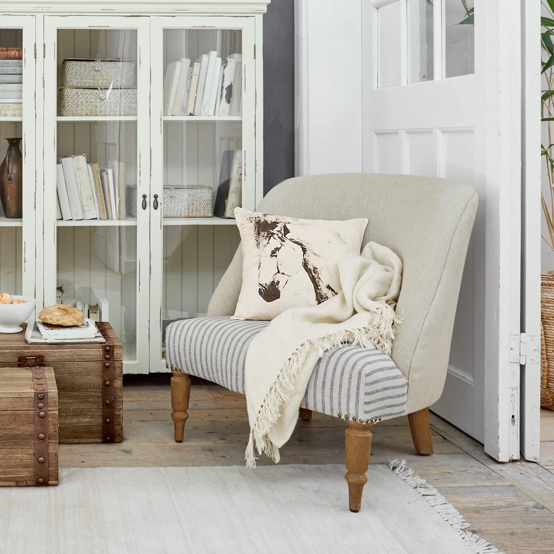 Tweekleurige bank van hout en stof in beige en grijs met kussen met paardenprint en deken