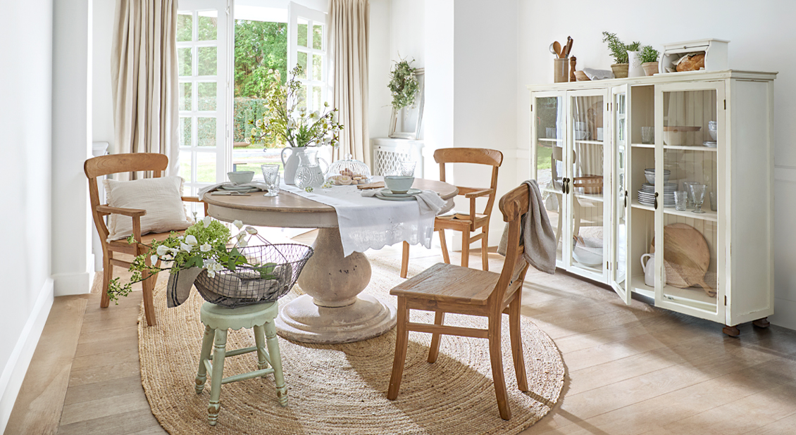 Lichte eetkamer met ronde houten tafel, rustieke stoelen en natuurlijke vloerkleed voor een gezellige sfeer