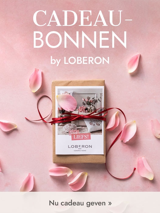 Cadeau verpakt in bruin papier met rood lint en roze rozenblaadjes op een roze achtergrond