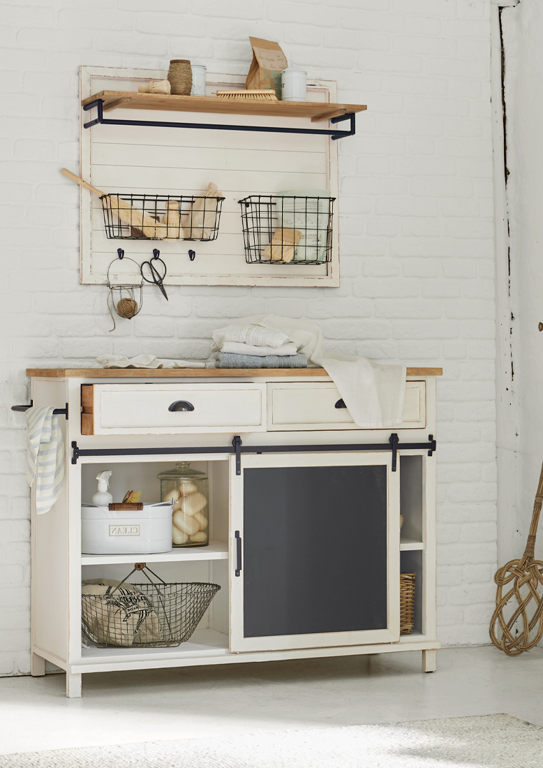 Witte houten kast met zwart schoolbord en metalen manden aan de muur, rustieke stijl