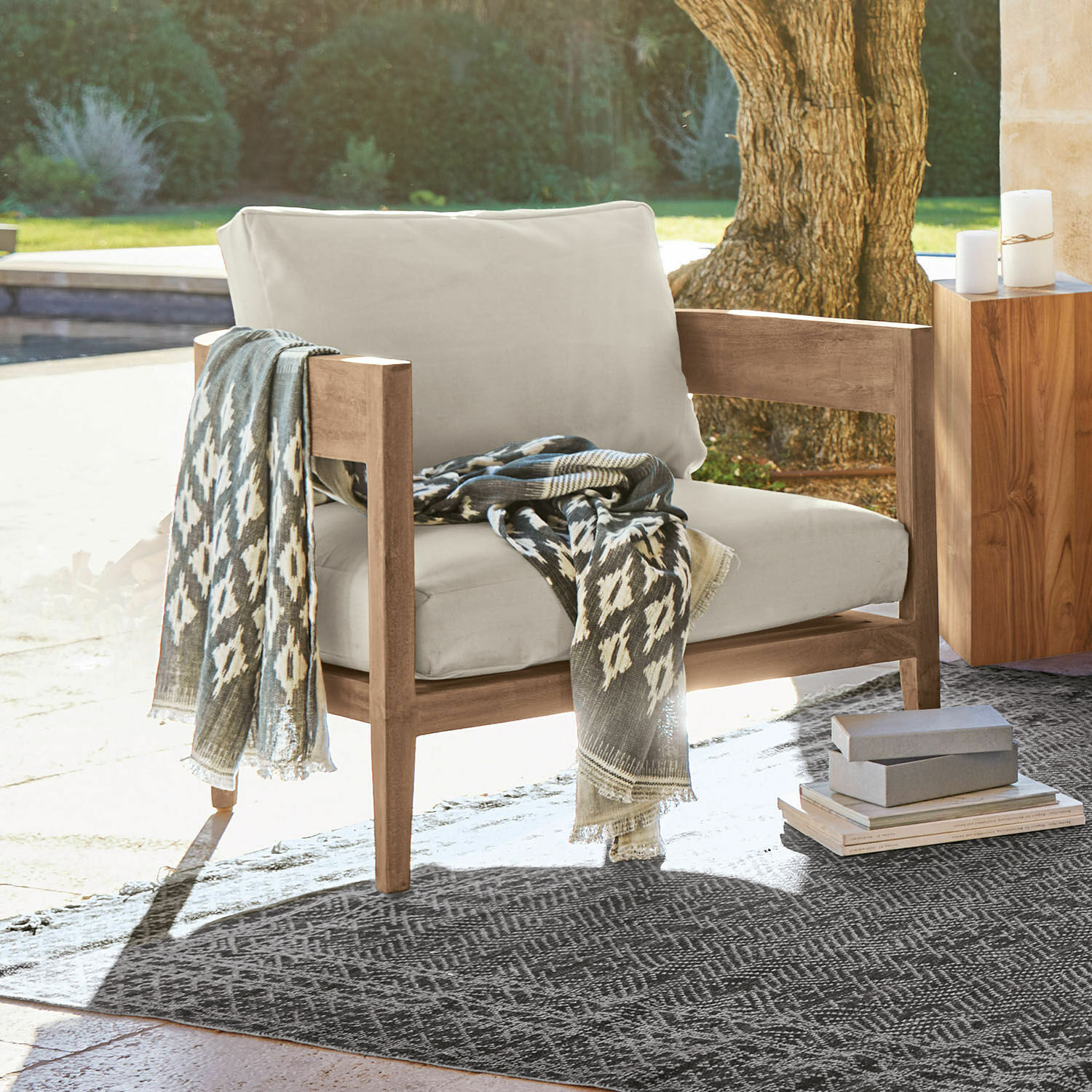 Fauteuil Courtelevant Fauteuil met lichtbeige bekleding en houten frame, grijze patroon deken op terras