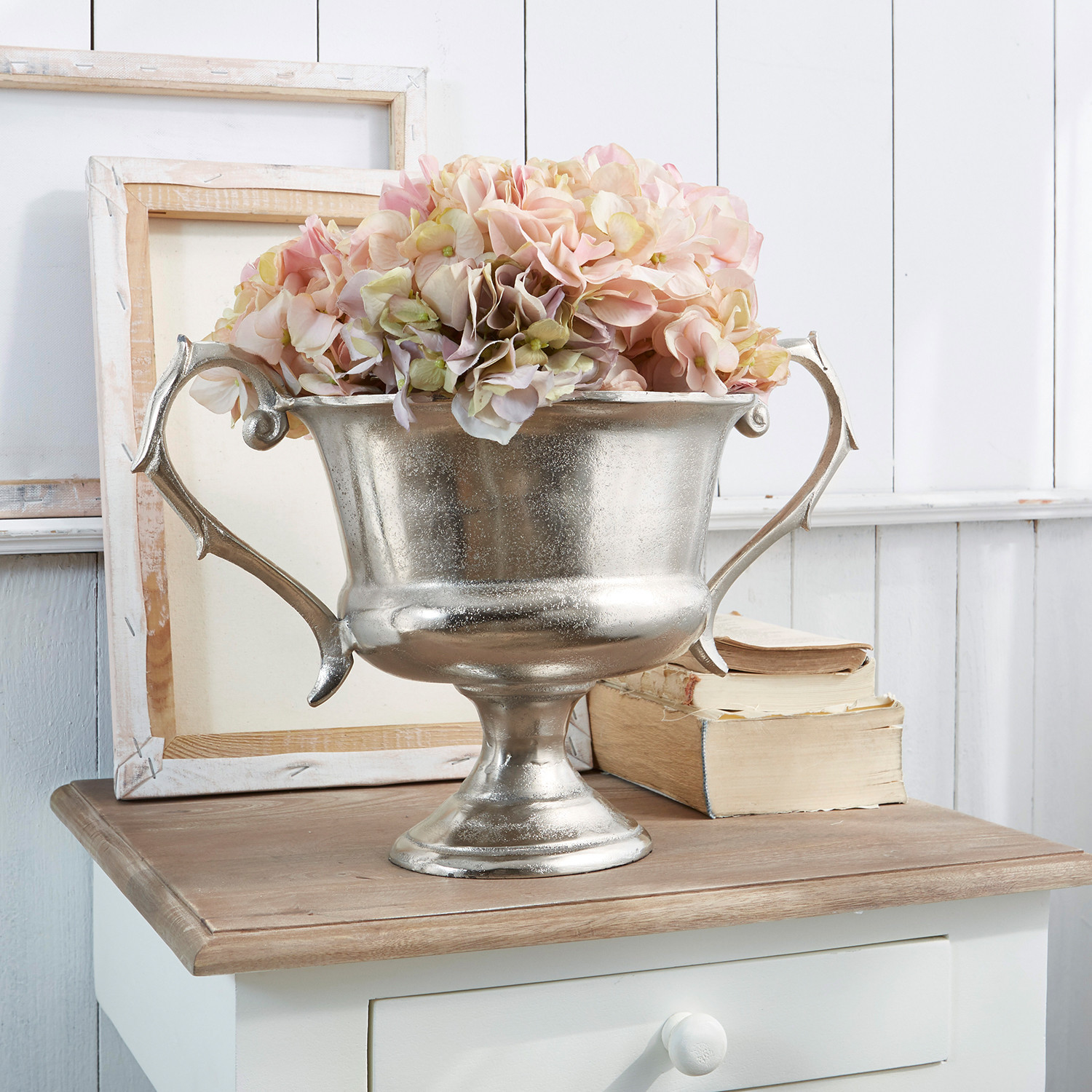 Bokaal Espère Zilveren metalen schaal met handvatten en roze bloemen op houten tafel, interieurdecoratie