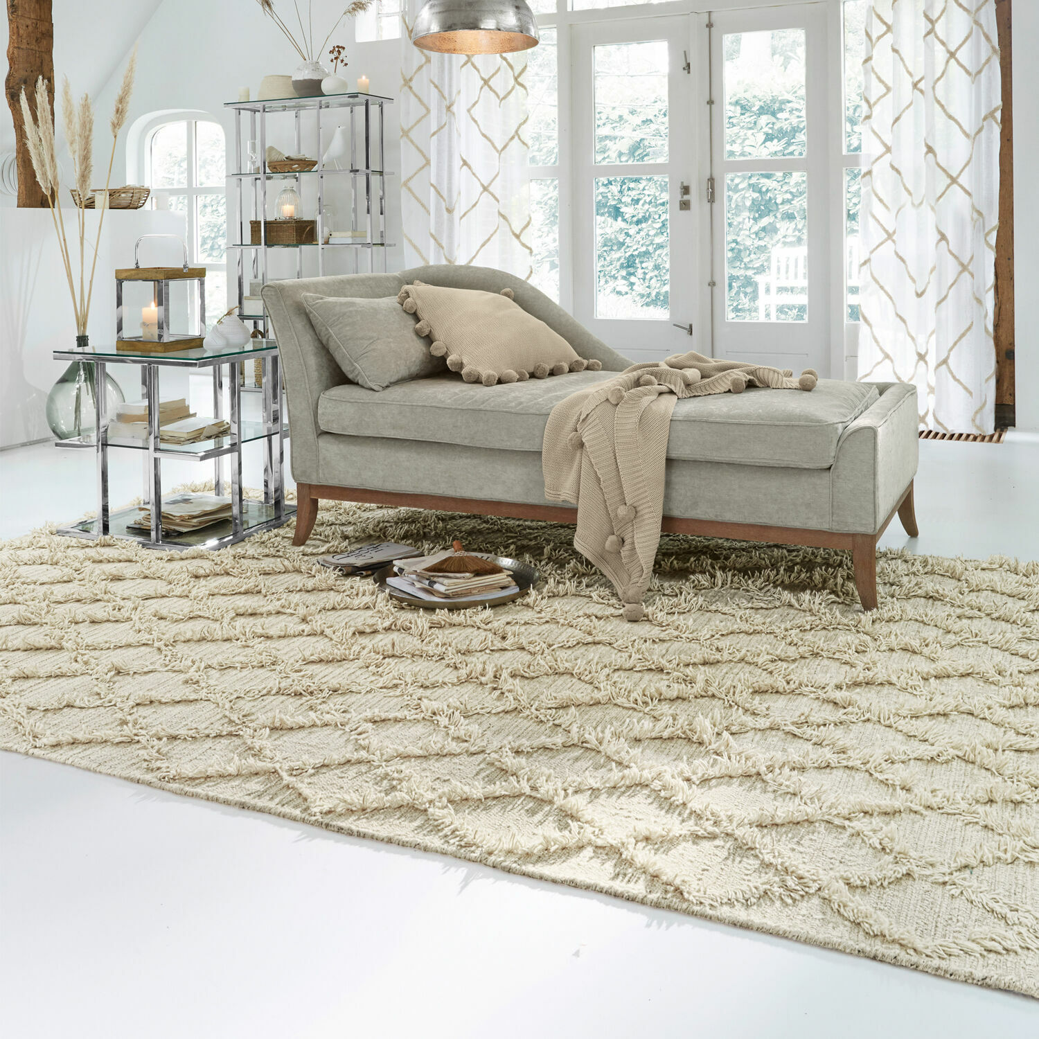 Grijze gestoffeerde chaise longue met houten poten op beige vloerkleed in lichte woonkamer