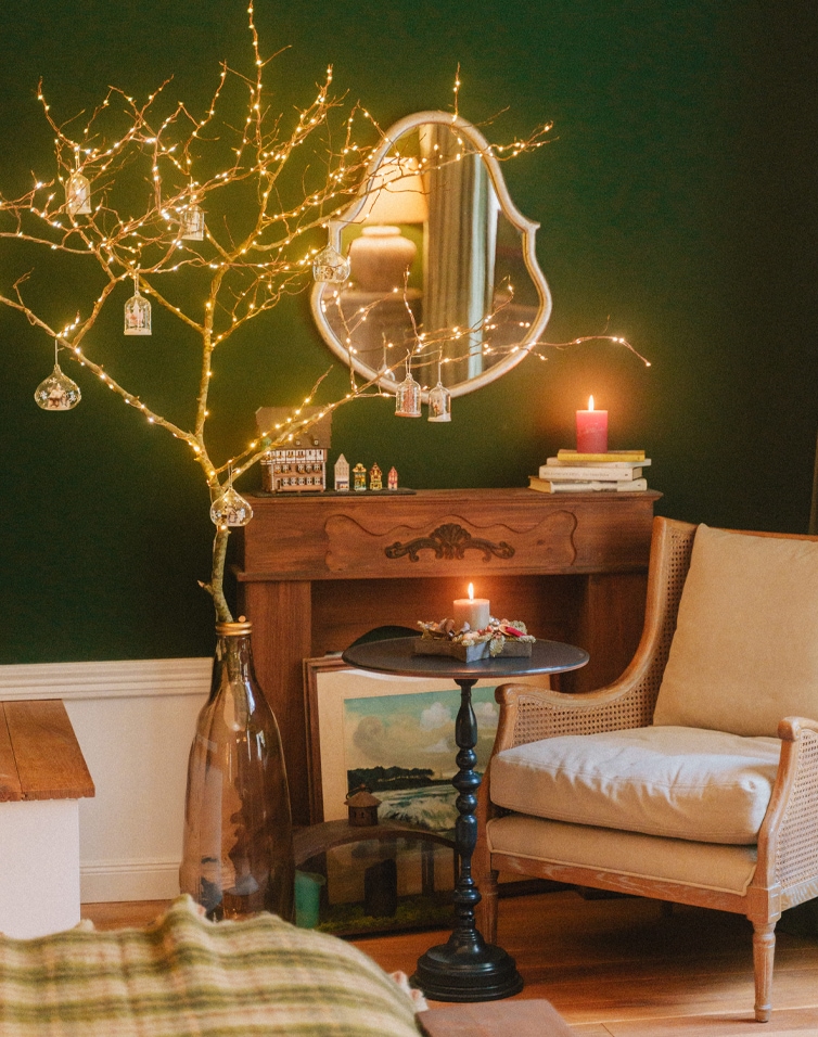 Gezellige woonkamer met beige fauteuil, zwarte tafel en kerstverlichting aan groene muur