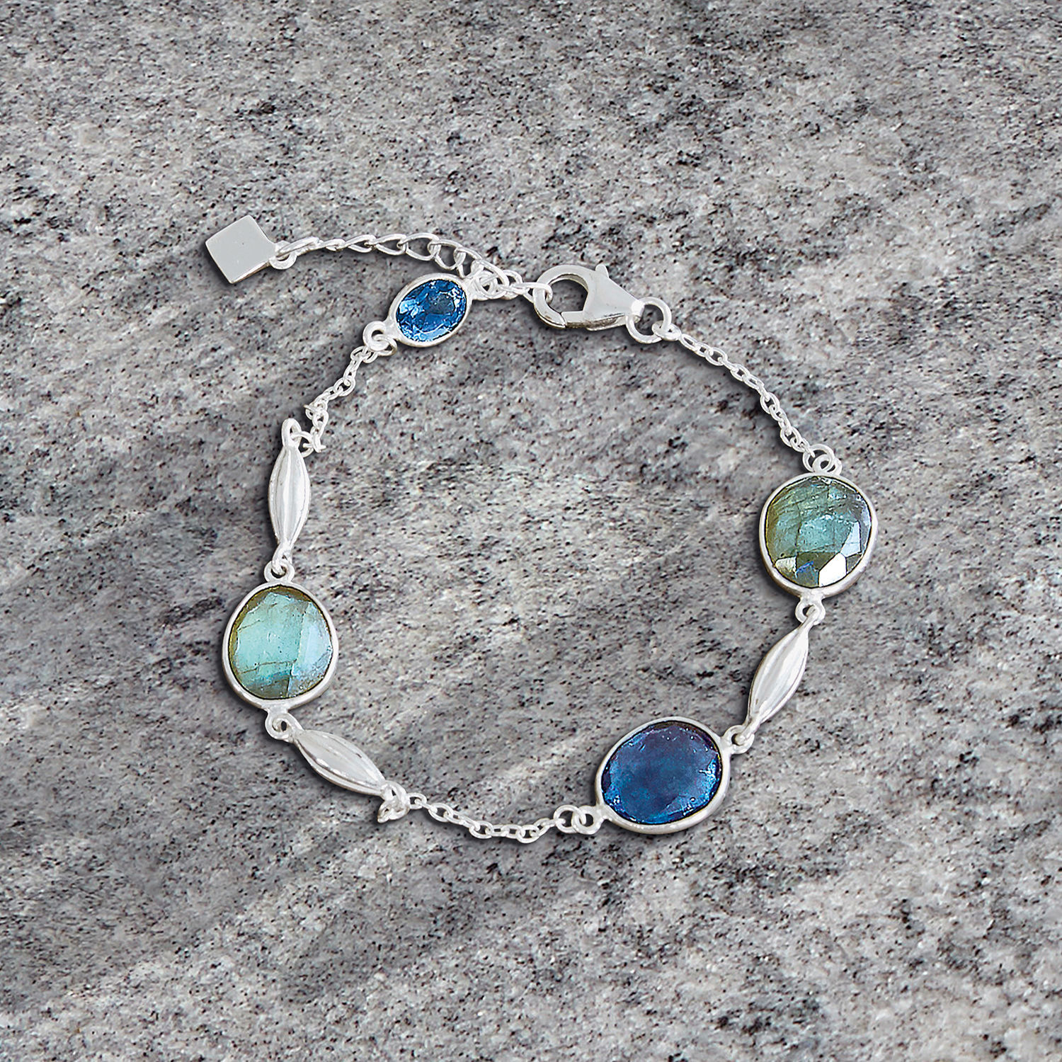 Fijn zilveren armband met blauwe en groene stenen op grijze achtergrond