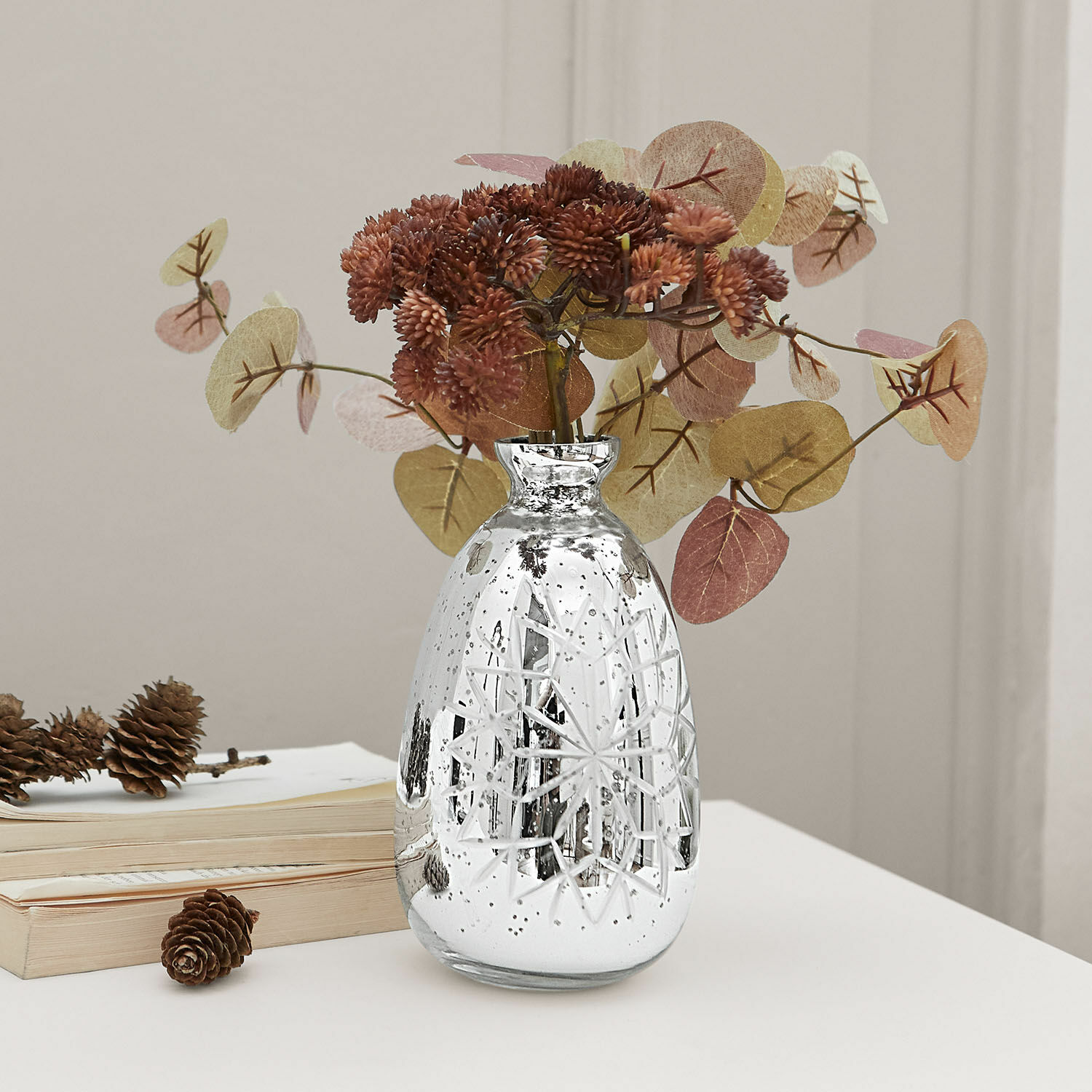 Vaas Zorelie Zilverkleurige glazen vaas met gegraveerd patroon en gedroogde bruine bloemen op witte tafel