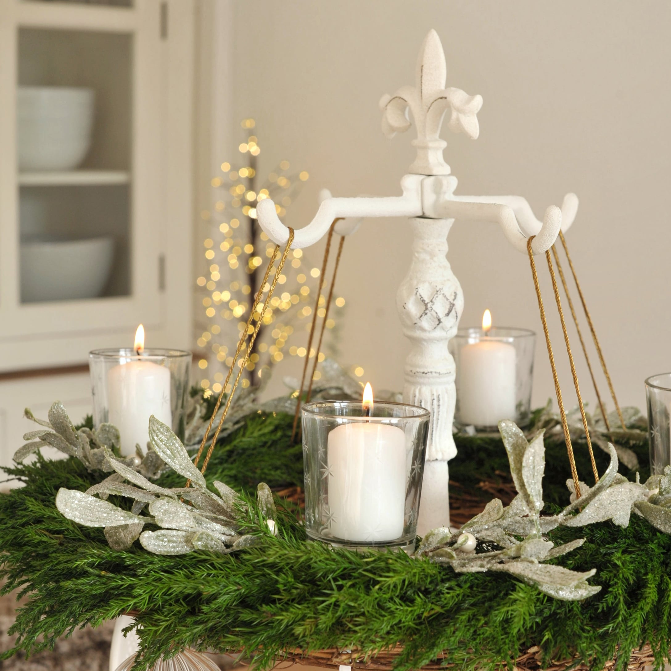Witte metalen adventskrans met groene krans en witte kaarsen, feestelijke decoratie