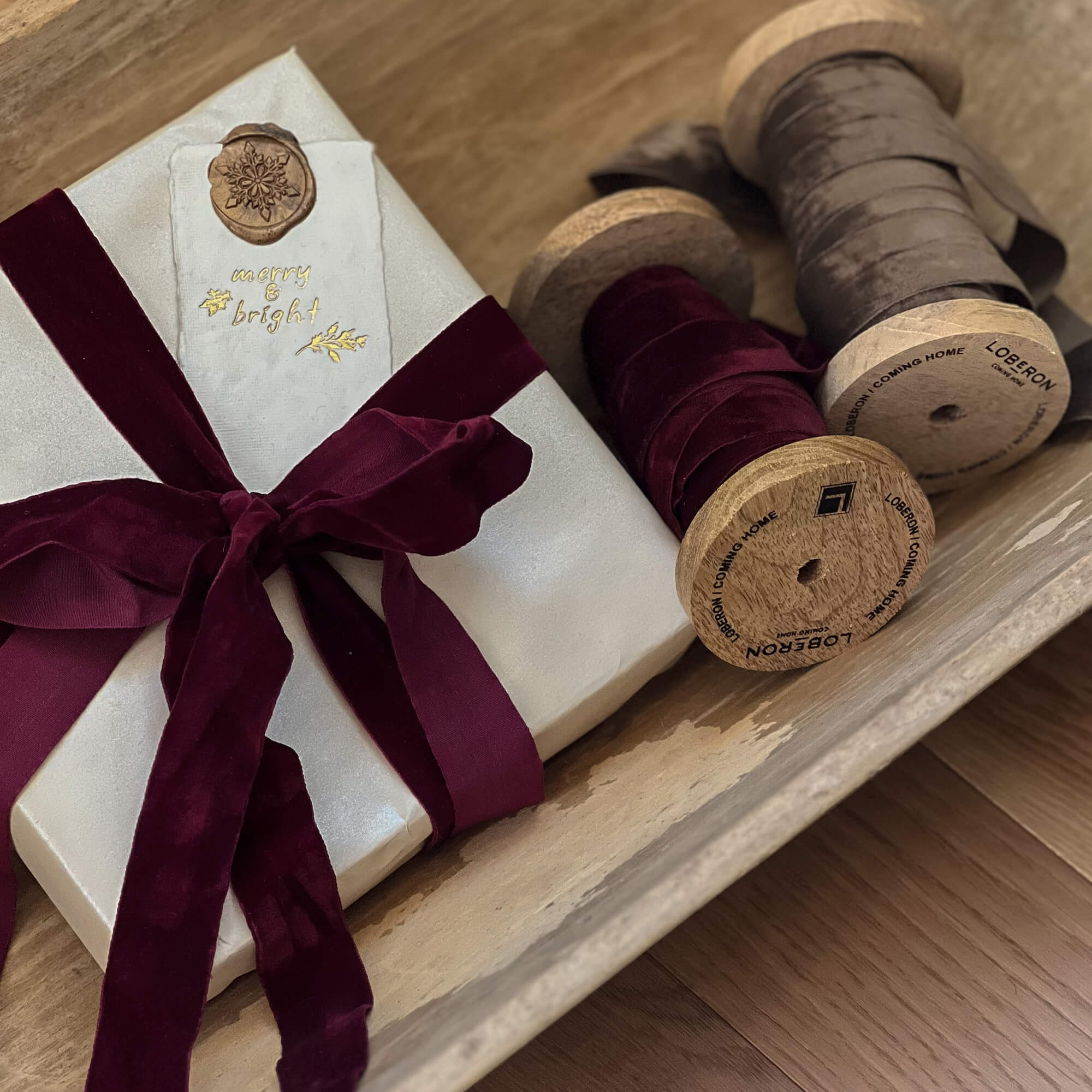 Stijlvol ingepakt cadeau met bordeauxrode fluwelen strik en houten spoelen met lint