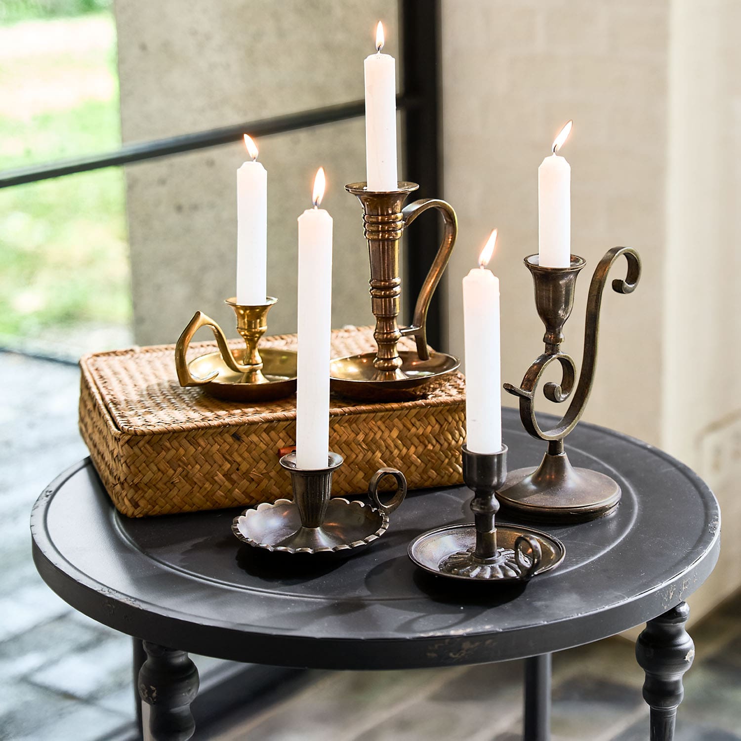 Set metalen kandelaars met witte kaarsen op een zwarte ronde tafel voor interieurdecoratie