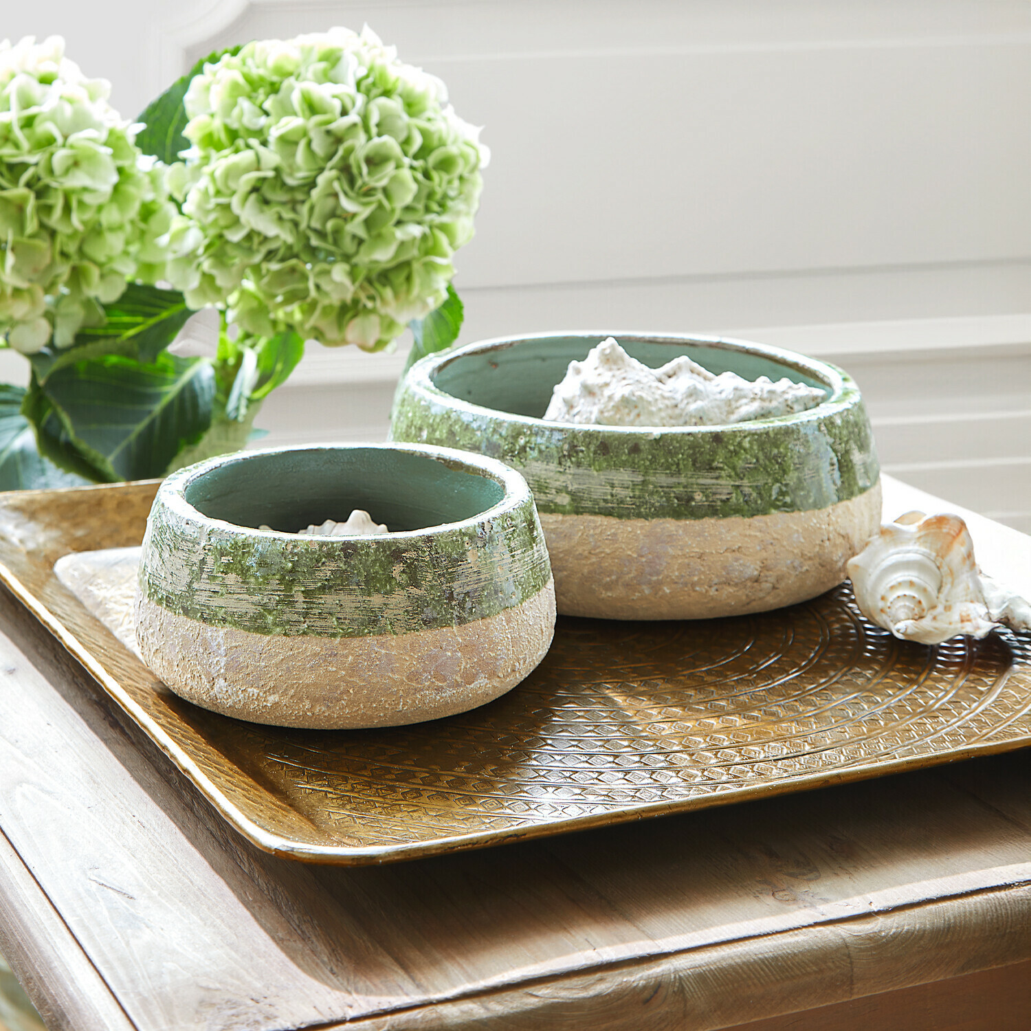 Twee keramische kommen in groen-beige op een decoratief gouden dienblad op houten tafel