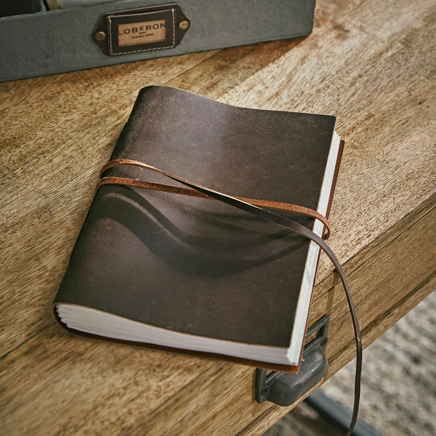 Bruin leren notitieboek met riem op houten bureau, praktisch schrijf- en notitieaccessoire