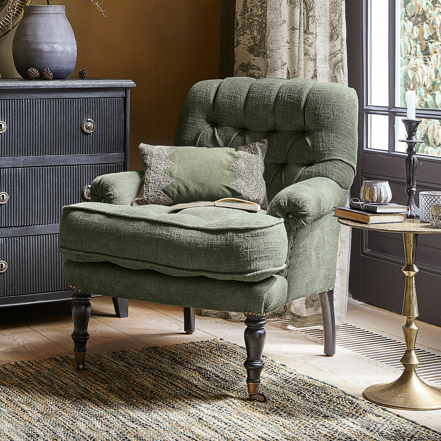 Stoel Gyldford Groene stoffen fauteuil met decoratief kussen in gezellige woonkamer met vloerkleed