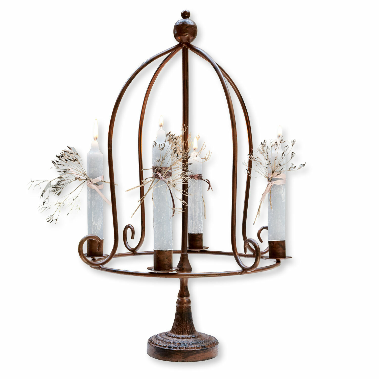 Metalen kandelaar in roestkleur met vier witte kaarsen en gedroogde planten als decoratie