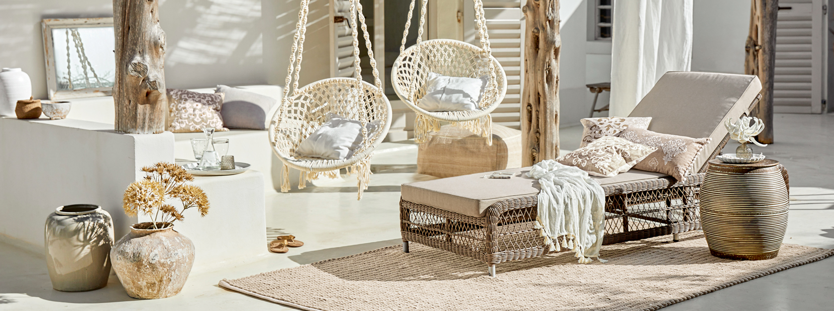 Gezellige lounge met rotan ligstoel en hangende katoenen stoelen in natuurlijke kleuren