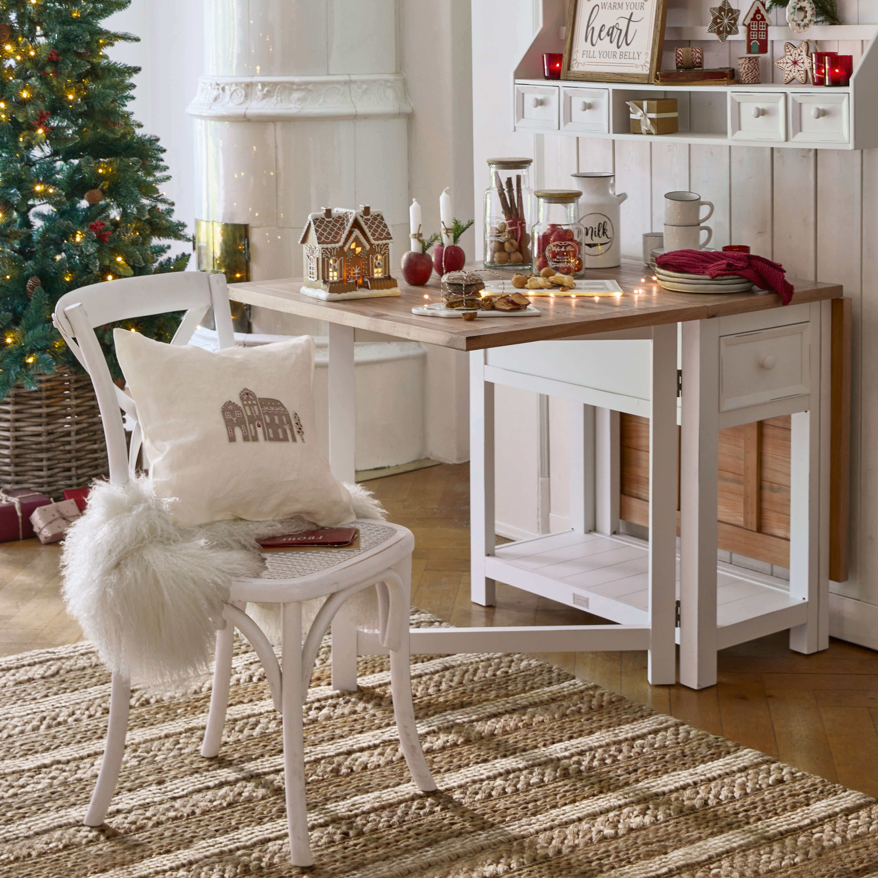 Gezellige witte houten tafel en stoel met kerstdecoraties en verlichte kerstboom op de achtergrond