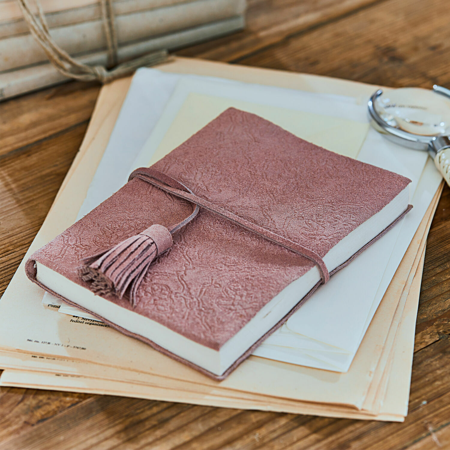Roze suède notitieboek met kwastje op houten tafel met documenten, schrijfgerei