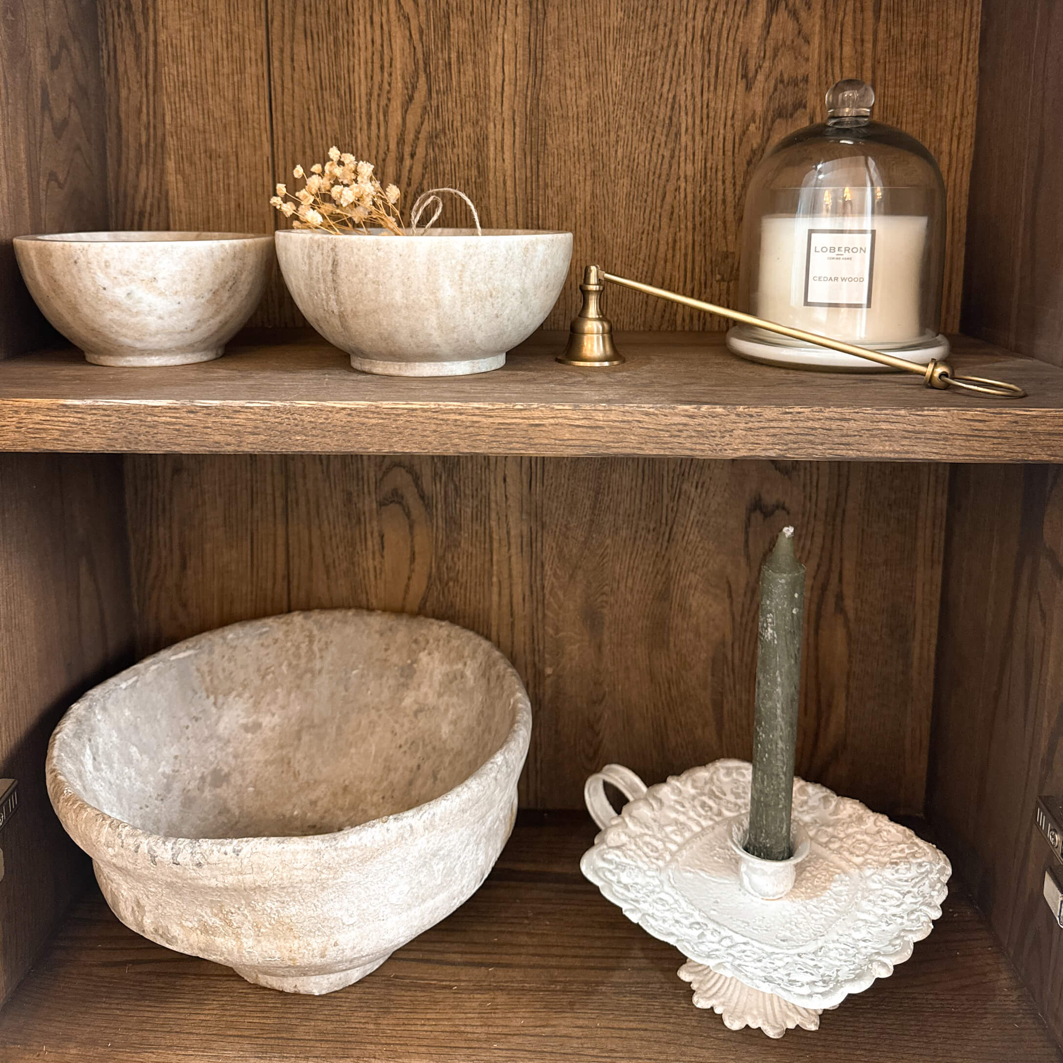 Decoratieve stenen kommen en kandelaar met groene kaars op rustiek houten plank