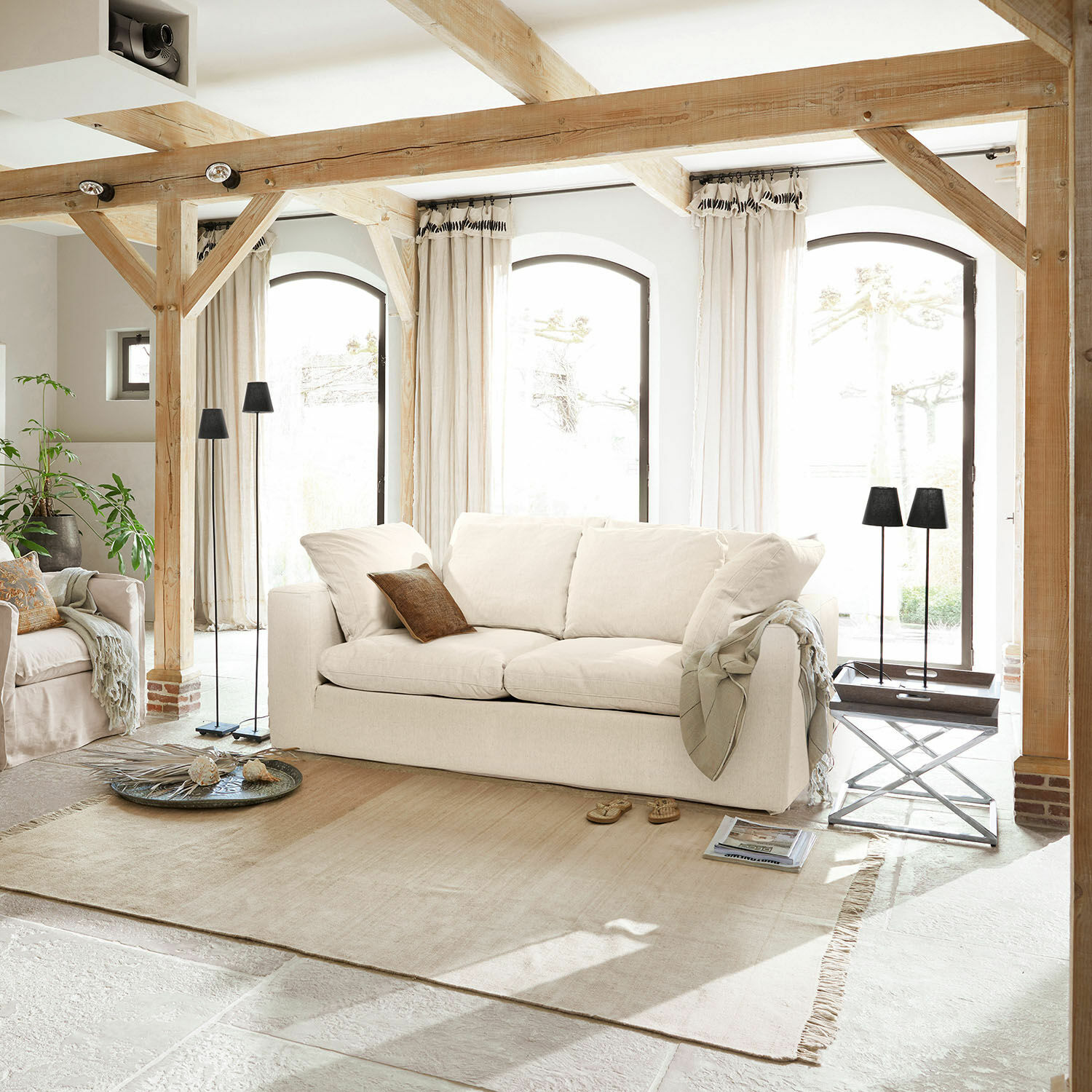 Sofa Xavreille Gezellige lichtbeige stoffen bank in lichte woonkamer met houten balken en lichte vloerkleed
