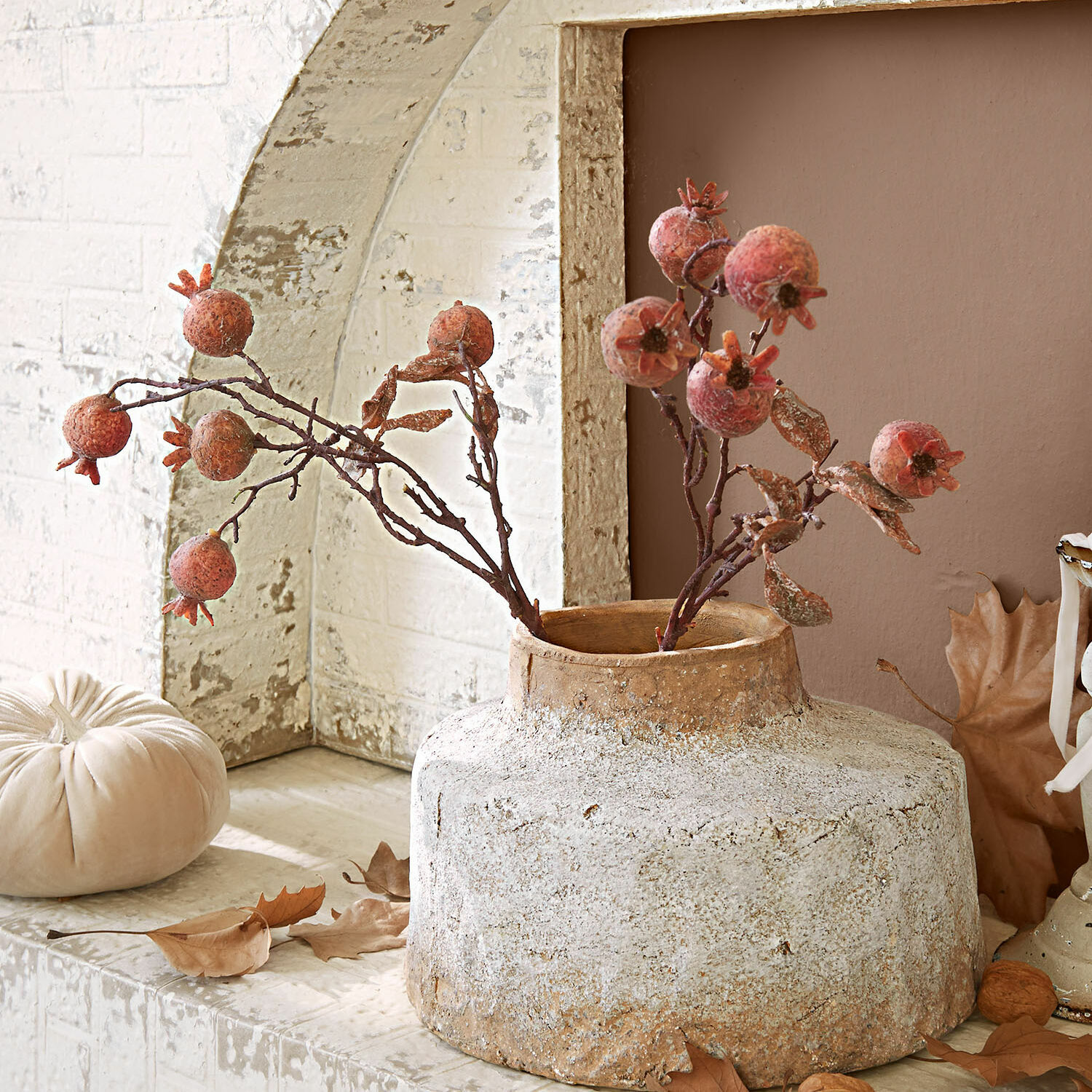 Rustieke beige keramische vaas met gedroogde granaatappel decoratie op plank