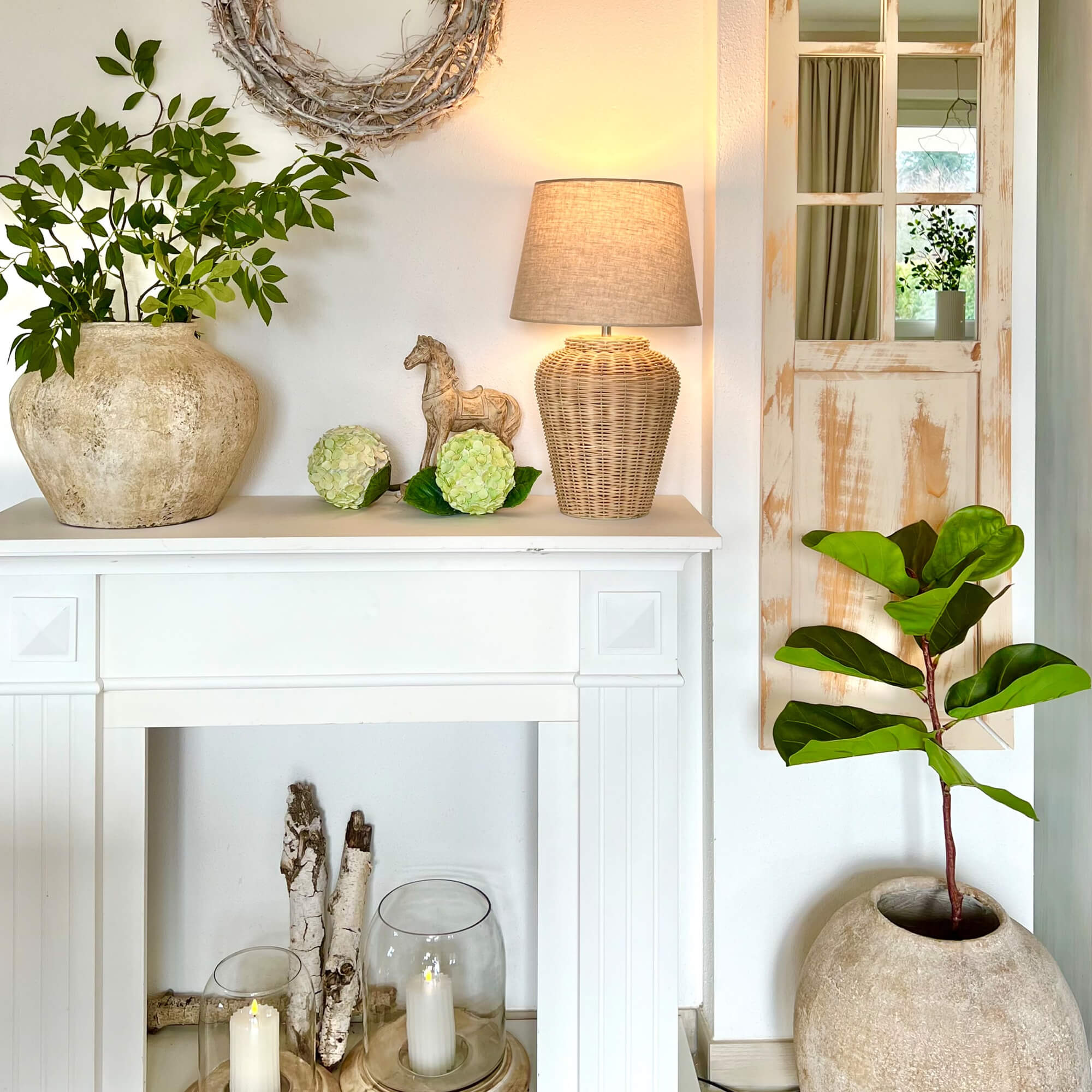 Witte decoratieve open haard met rotan lamp en groene planten in stenen potten