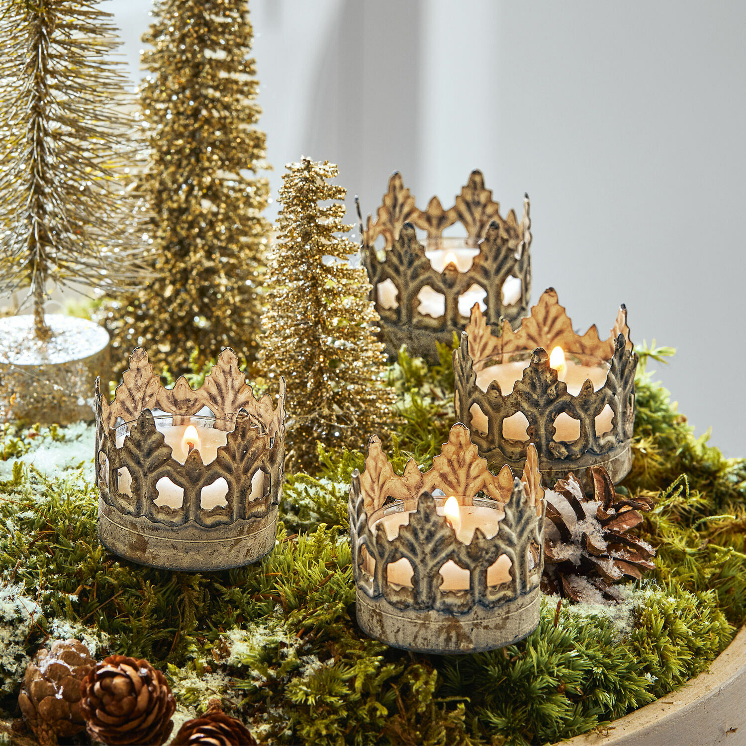 Insteekwindlicht set van 4 Groisy Metalen kandelaren in kroonvorm op groen mos met kerstdecoratie en brandende kaarsen