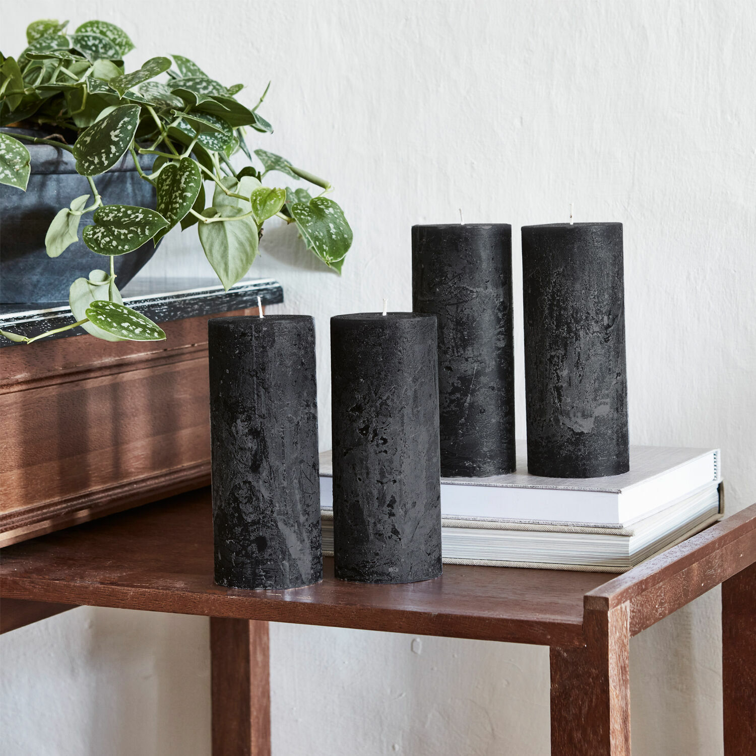 Kaars set van 4 Homel Vier zwarte waskaarsen op een houten tafel naast een groene kamerplant in pot